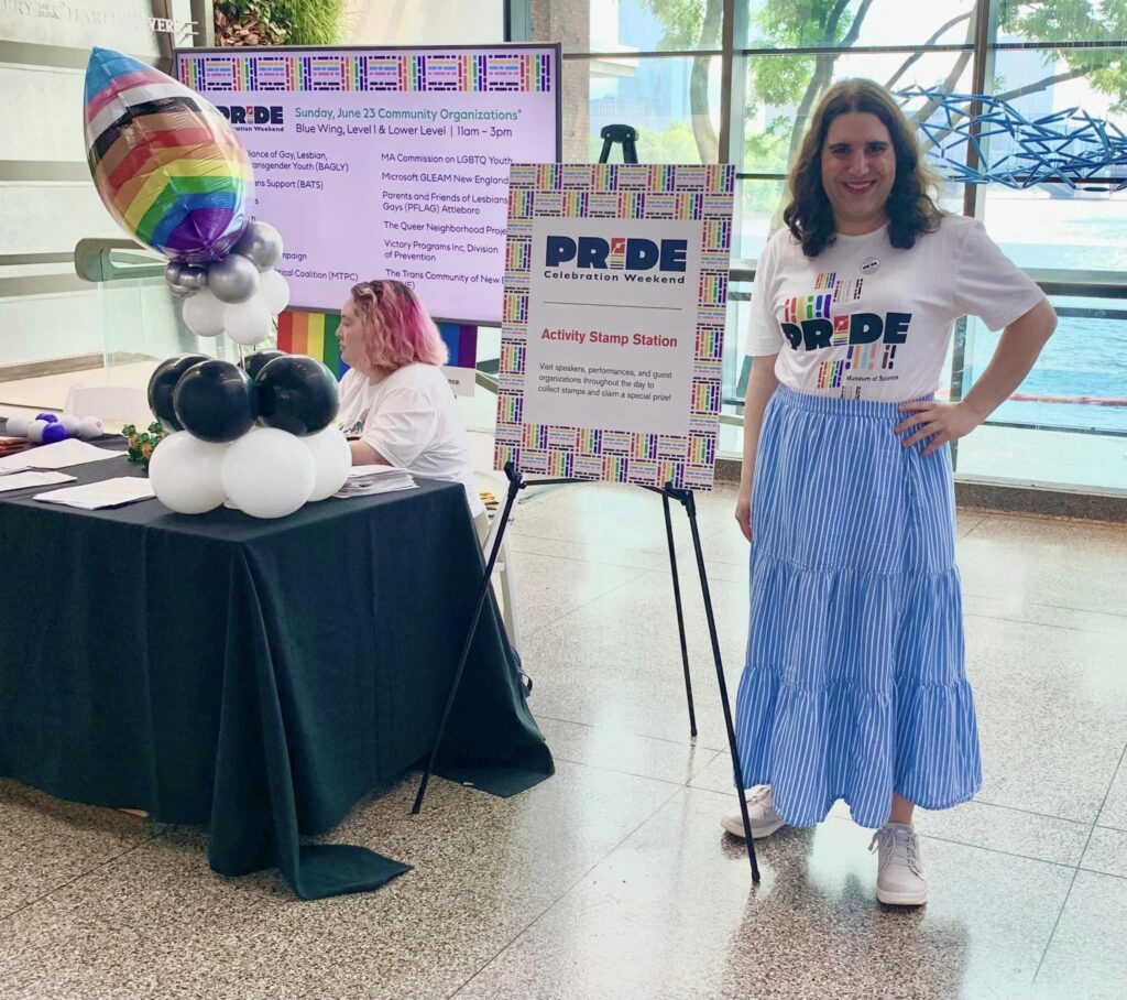 Me with the prize table at the Museum of Science, Boston for Pride celebration weekend in June 2024.