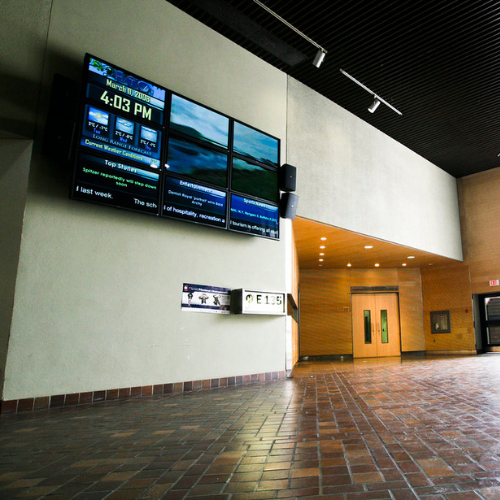 An image of a corridor with a digital sign monitor on it.